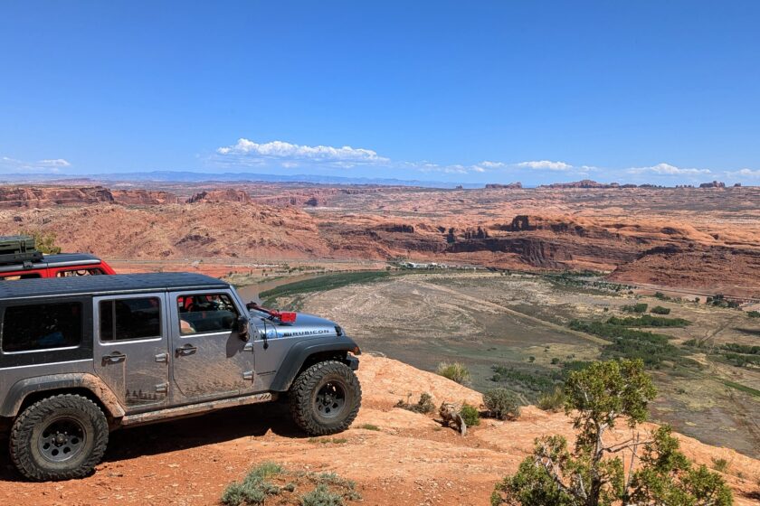 Photo of two Jeeps parked side by side overlooking the Colorado River valley and the city of Moab from Poison Spider trail.